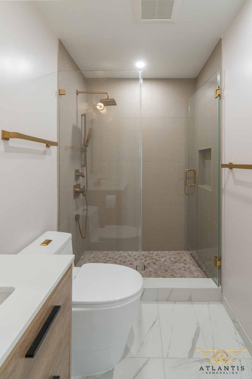 Walk-in shower with glass enclosure, gold hardware, and hex floor tile