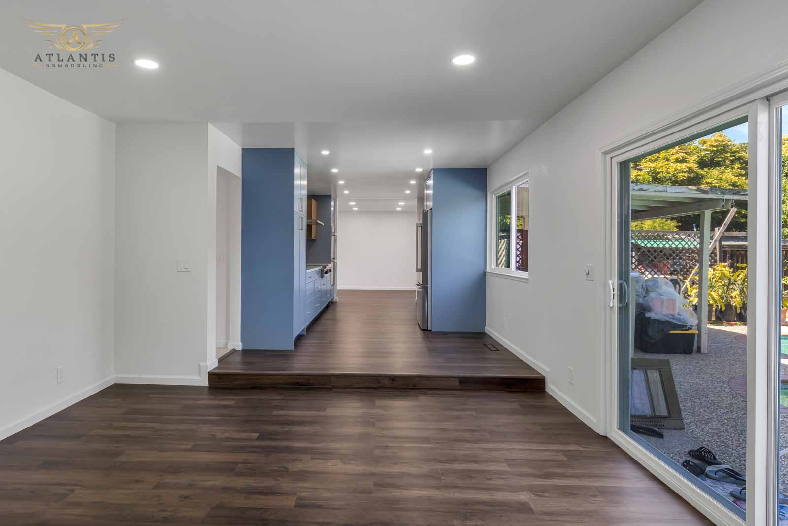 Open living area with blue accent walls, hardwood floors, and sliding glass door to backyard