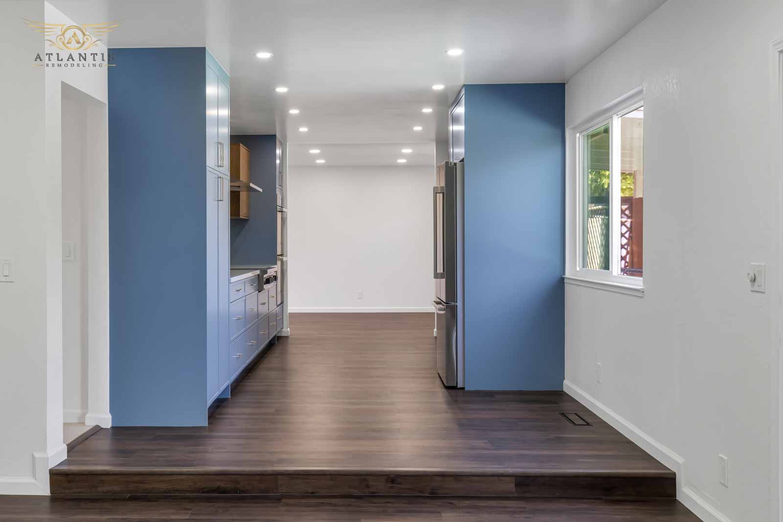 Blue accent kitchen with oak upper cabinets, stainless steel fridge, and hardwood flooring