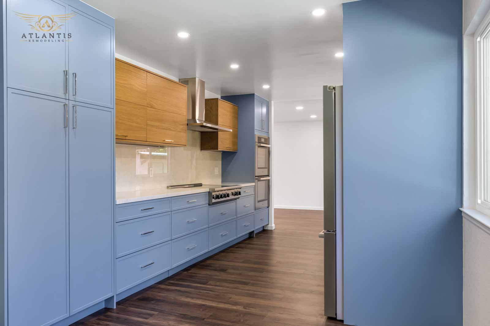 Blue shaker cabinets with oak upper cabinets, professional range, and hood vent