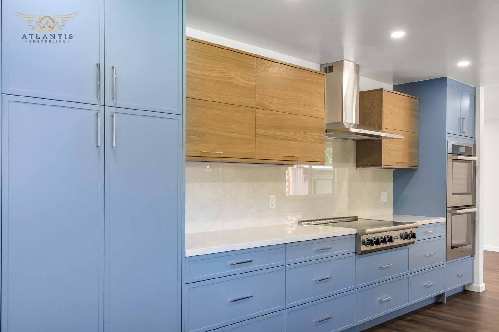 Close-up of blue cabinets with oak uppers, professional range, and quartz countertops